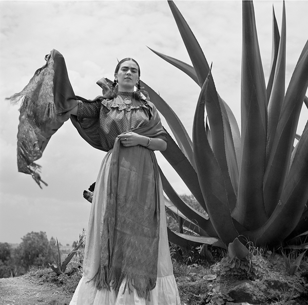 Frida Kahlo standing next to an agave plant
