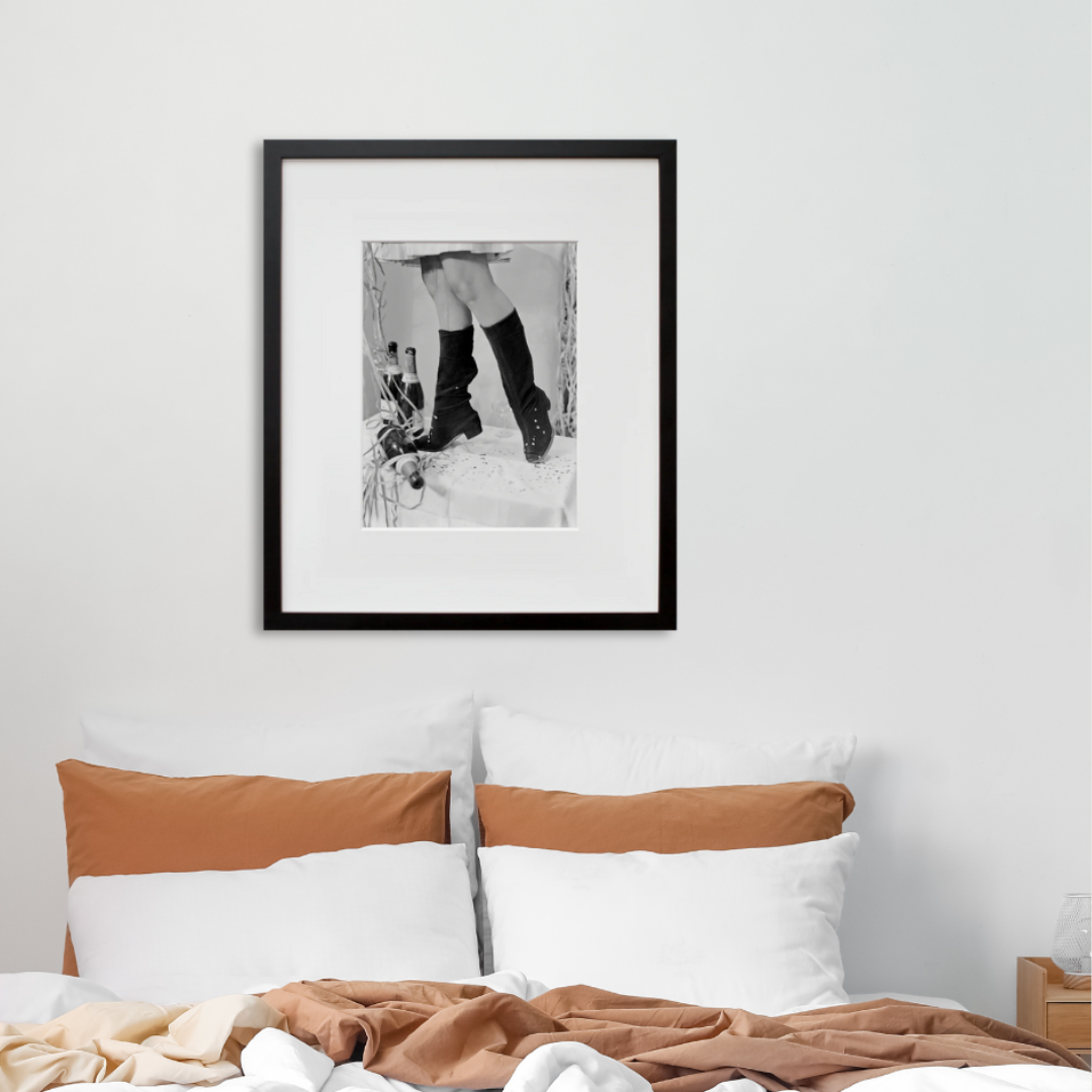 Untitled (Boots & Champagne) in a black frame on a wall
