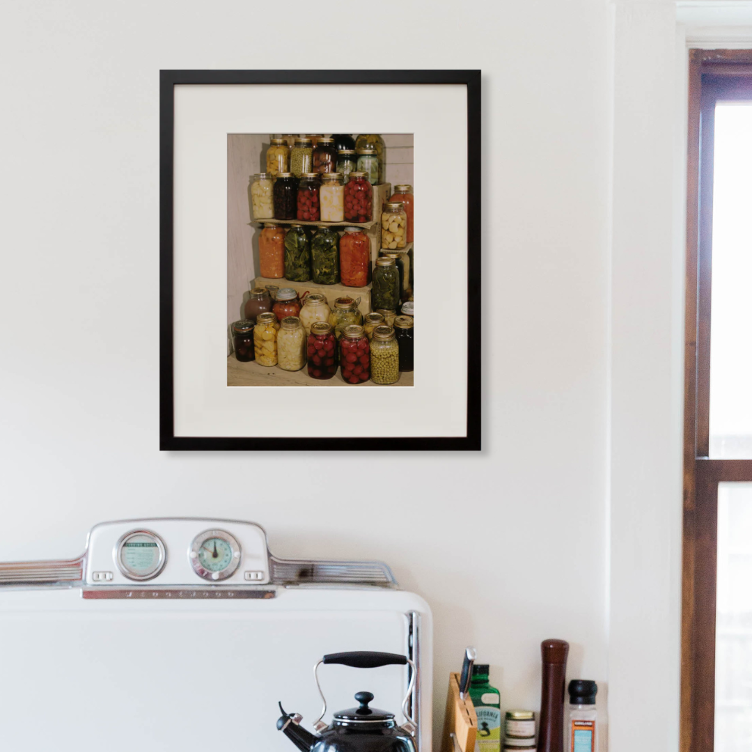 Display of home-canned food in a black frame on a wall
