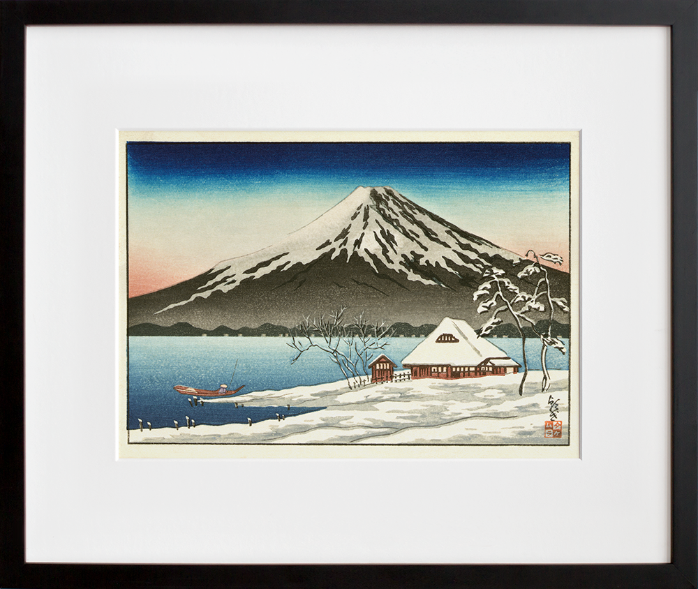 Winter landscape with small snow-covered building on the coast and view of Mount Fuji in a black frame
